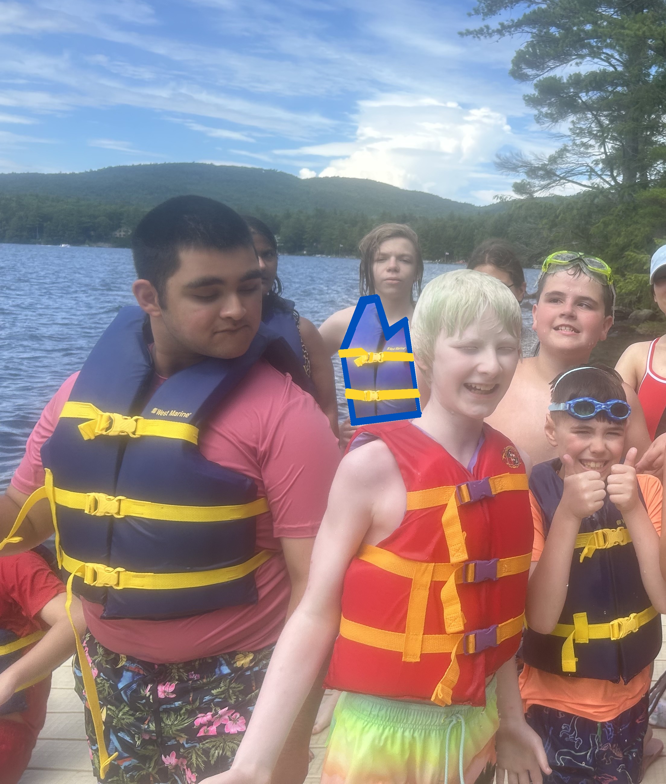 Group of smiling campers on the dock ready to go for a swim in the lake.